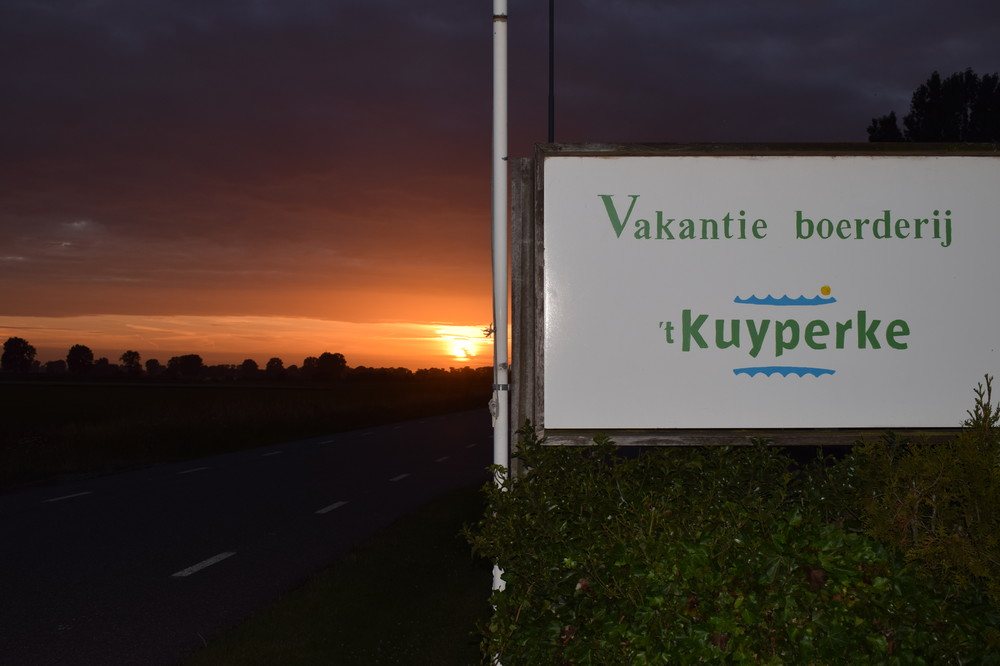 Zonsondergang bij het bord aan de dijk